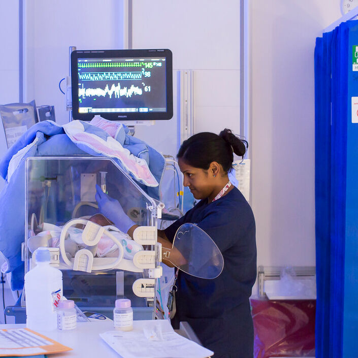 Nurse caring for baby in incubator
