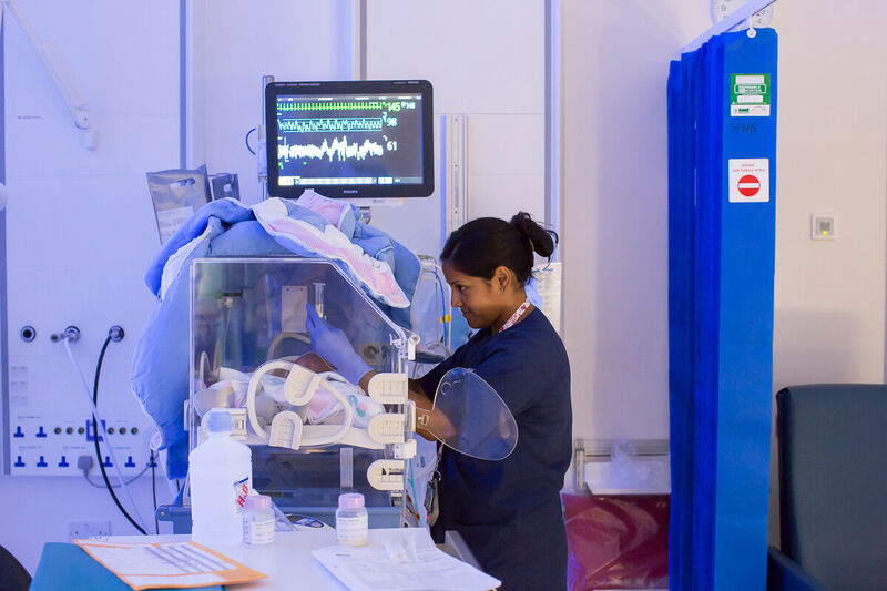 Nurse caring for baby in incubator
