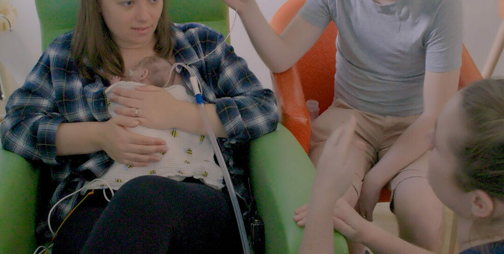 Nurse talking to parents while the mother has the baby resting on her chest.