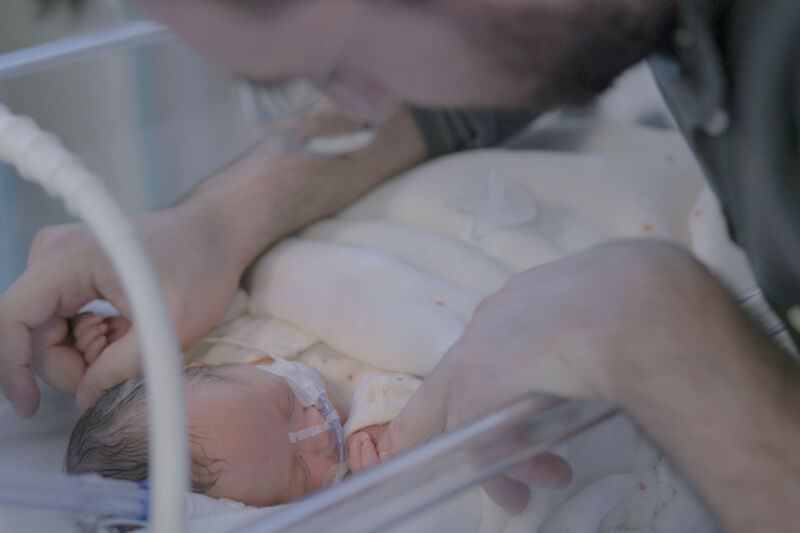 Father looking down and caressing his sleeping baby.
