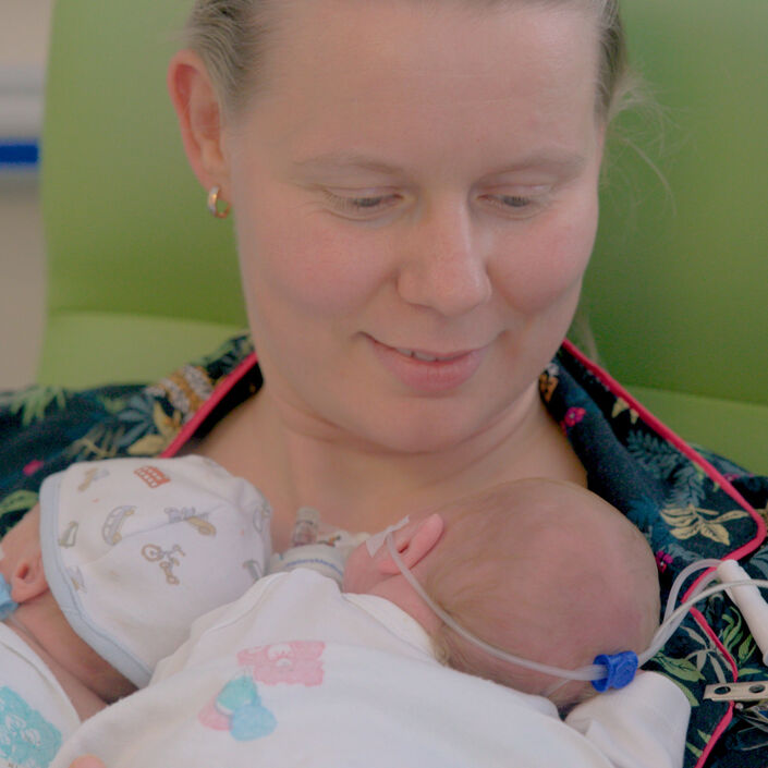Mother in hospital with her twin babies laying on her chest.