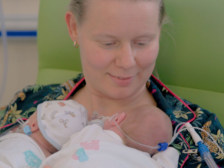 Mother in hospital with her twin babies laying on her chest.
