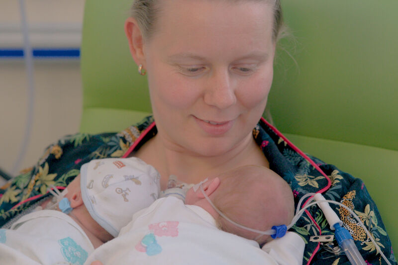 Mother in hospital with her twin babies laying on her chest.