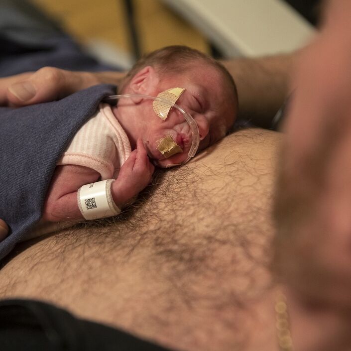 A dad who has baby on chest doing skin to skin care