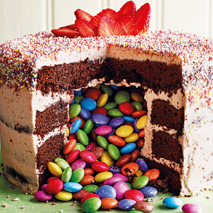 Cake with slice taken out and smarties tumbling out from the middle
