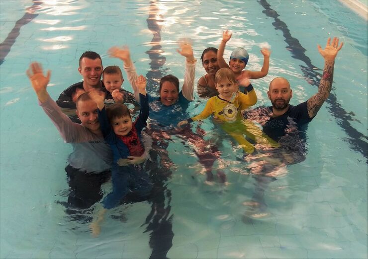 Children with their parents in a swimming pool wearing pyjamas