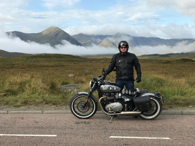Man next to Motorbike with Mountains in background