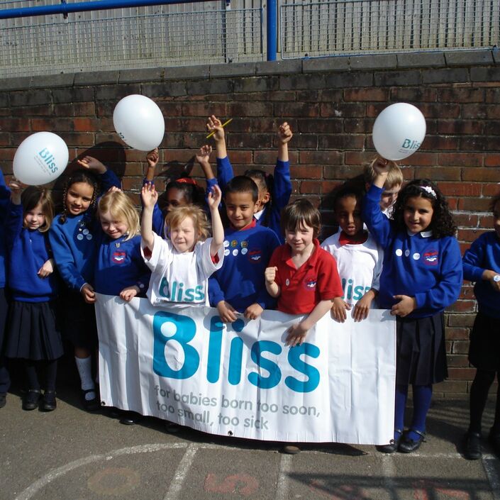 group of school children with Bliss banner and balloons