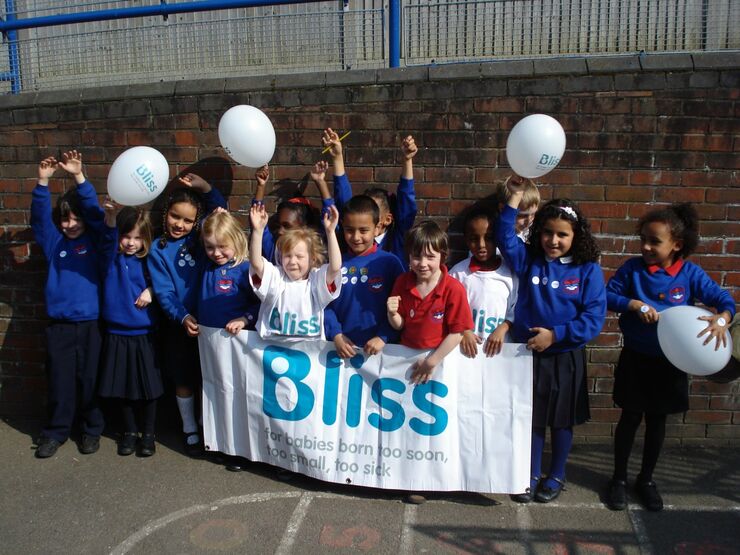 group of school children with Bliss banner and balloons