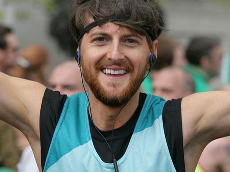 Head shot of man running celebrating with arms in the air at an event wearing a Bliss running vest