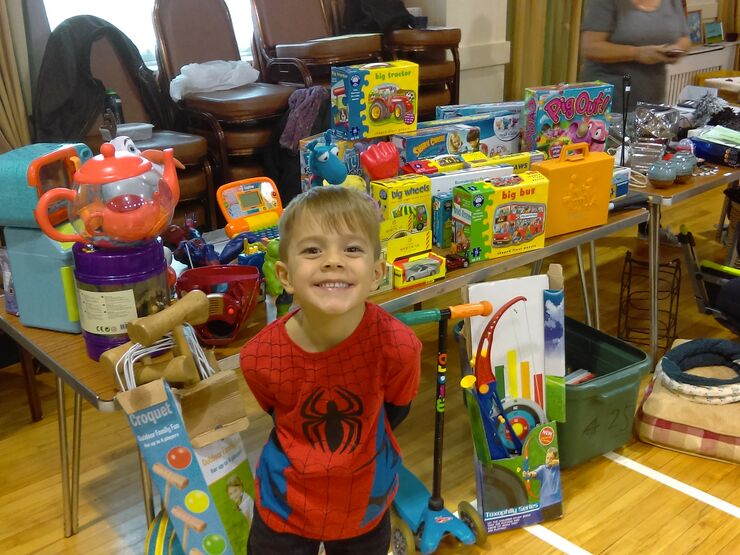 Young boy in spider man costume in front of his toys