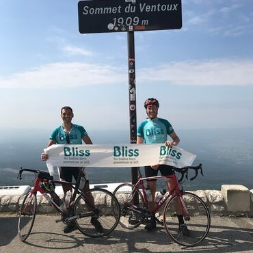 Two Bliss cyclists holding Bliss banner