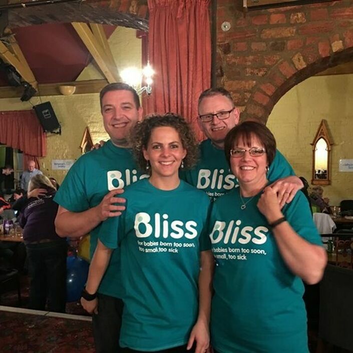 Group of 4 wearing Bliss t-shirts in a venue where they have organised an event