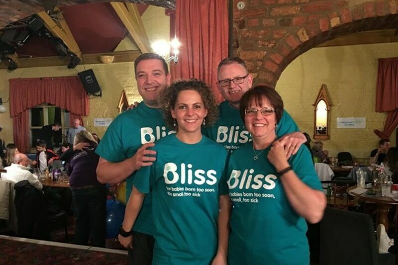 Group of 4 wearing Bliss t-shirts in a venue where they have organised an event