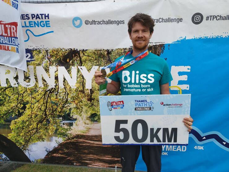 Man in bliss t-shirt with medal having finished 50km challenge