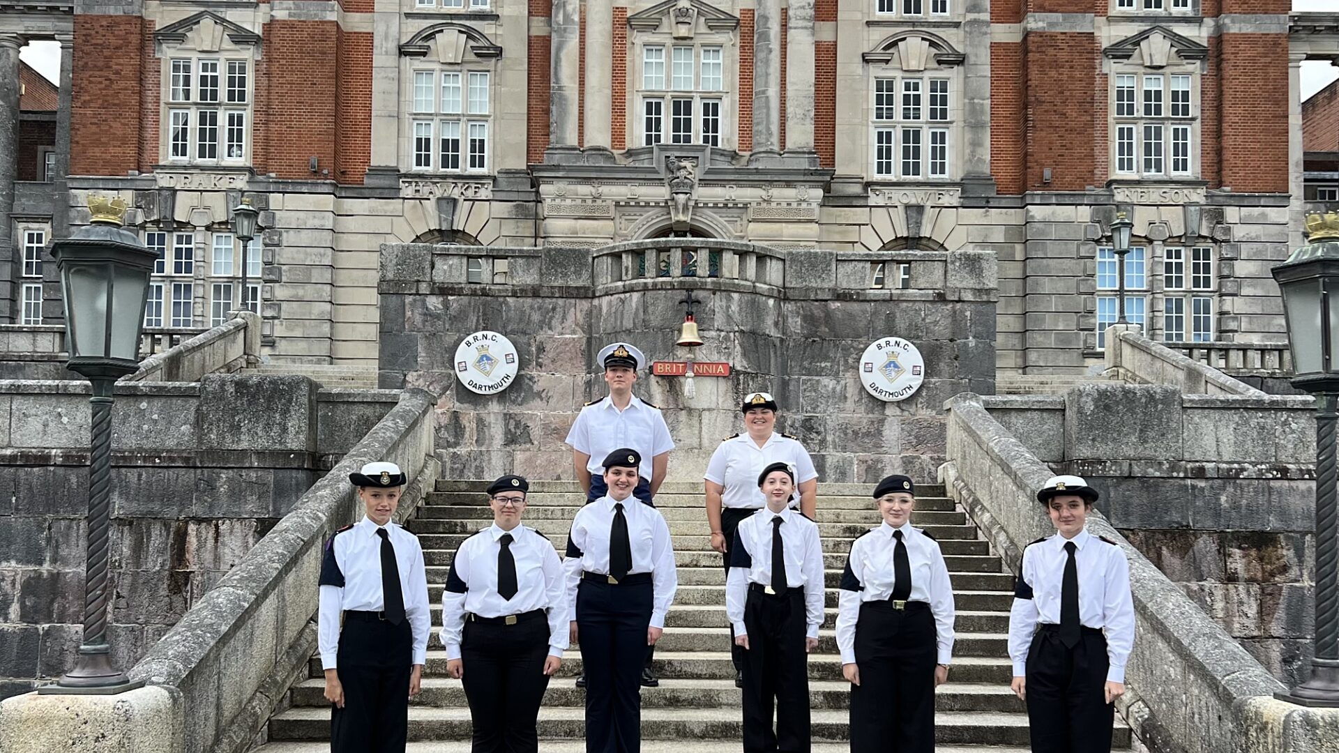 Group of CCF Royal Navy Cadets standing in front of the Naval Collage wearing white shirts and black ties
