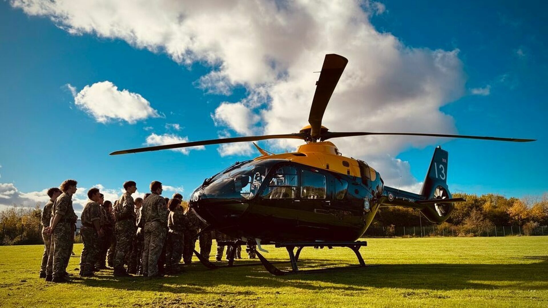 CCF Cadets gather around a helicopter that has landed in a field