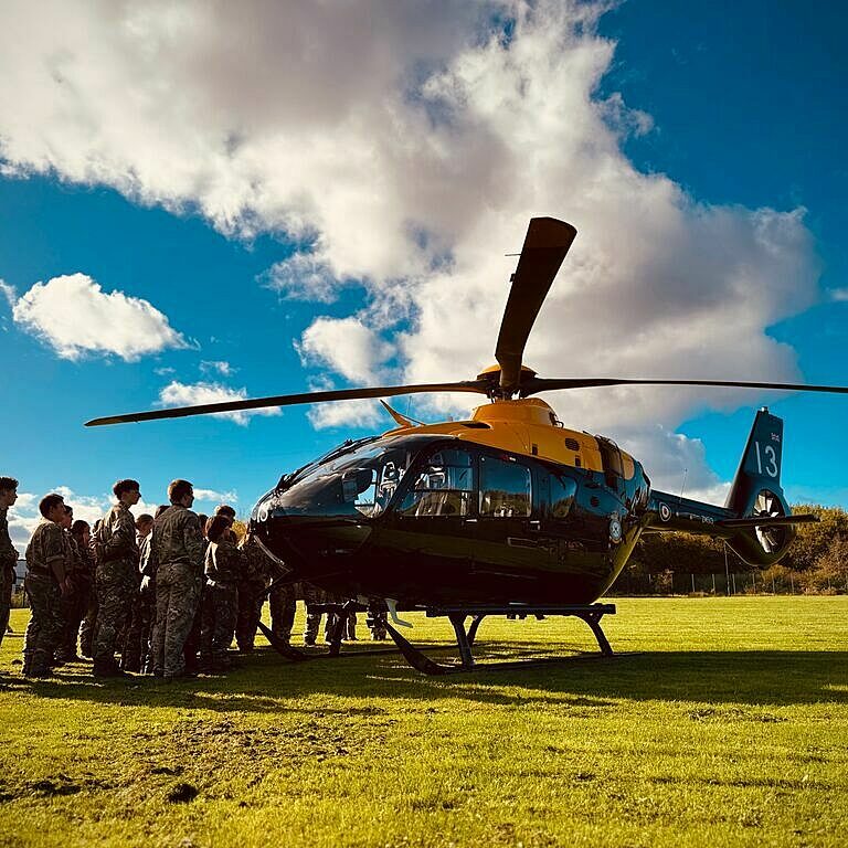 CCF Cadets gather around a helicopter that has landed in a field