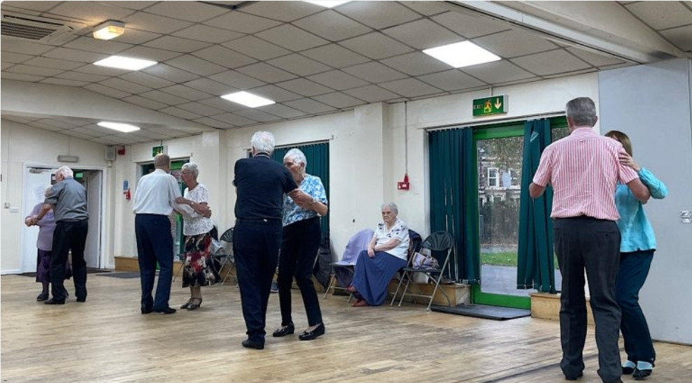 Elderly couples dancing together in a bright hall while others sit and watch quietly | Catherine Beckett Centre