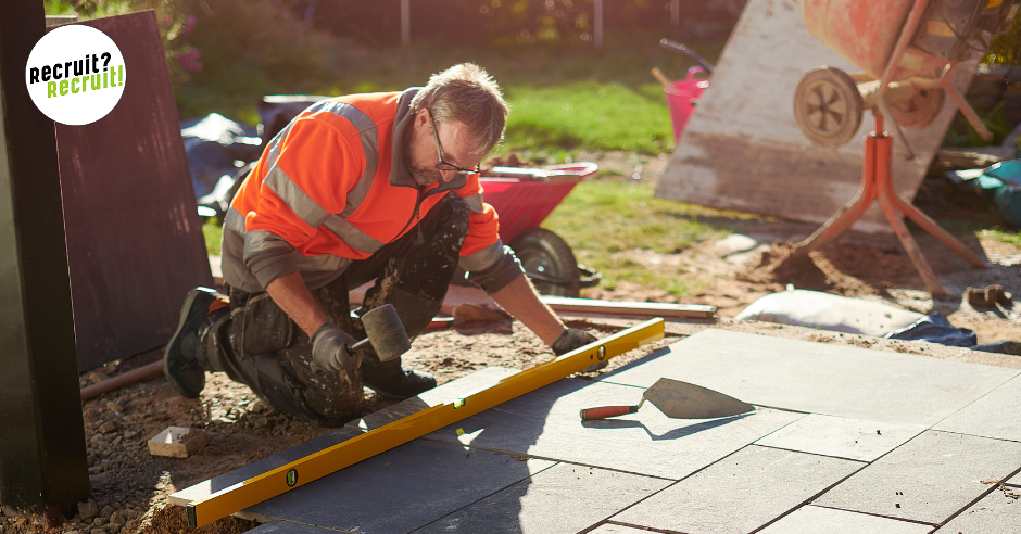 man using spirit level to lay paving slabs