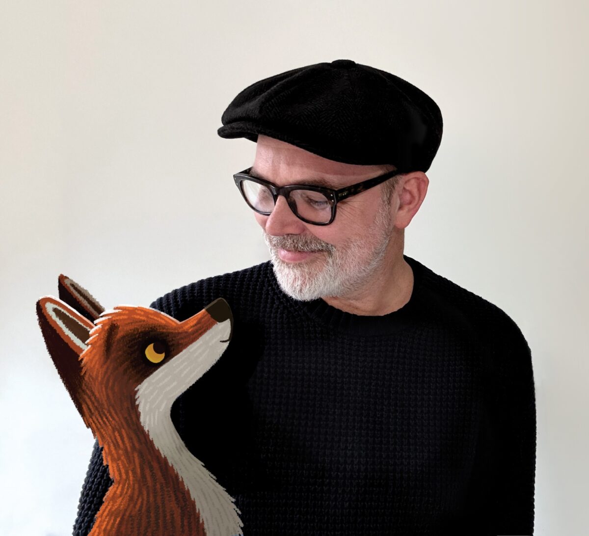 A man wearing a black jumper and a black hat looks down at a cartoon drawing of a fox, edited onto the picture.