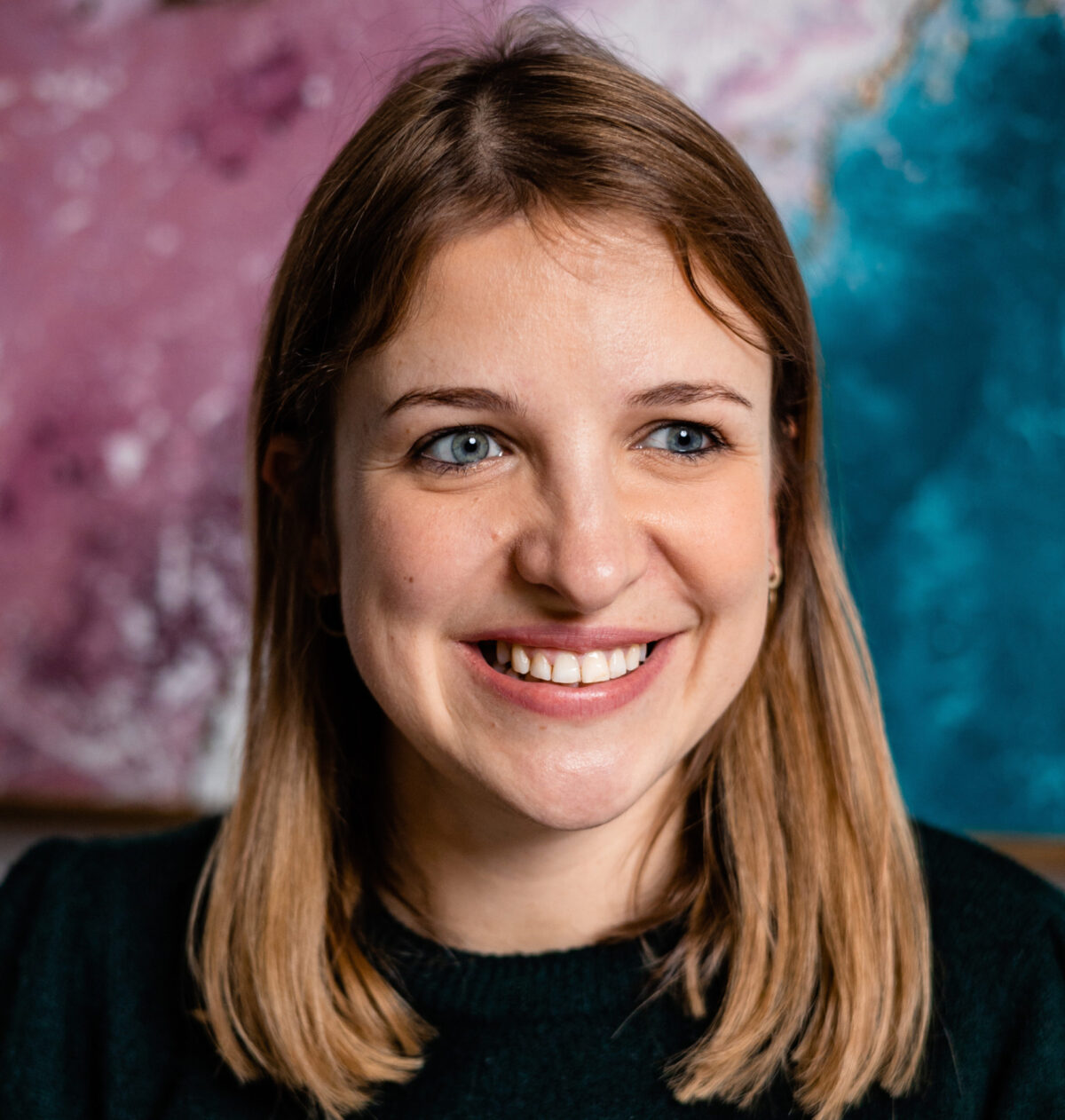 Photo headshot shows Ewa, a woman smiling towards the camera. She has brunette hair in a bob and blue eyes.