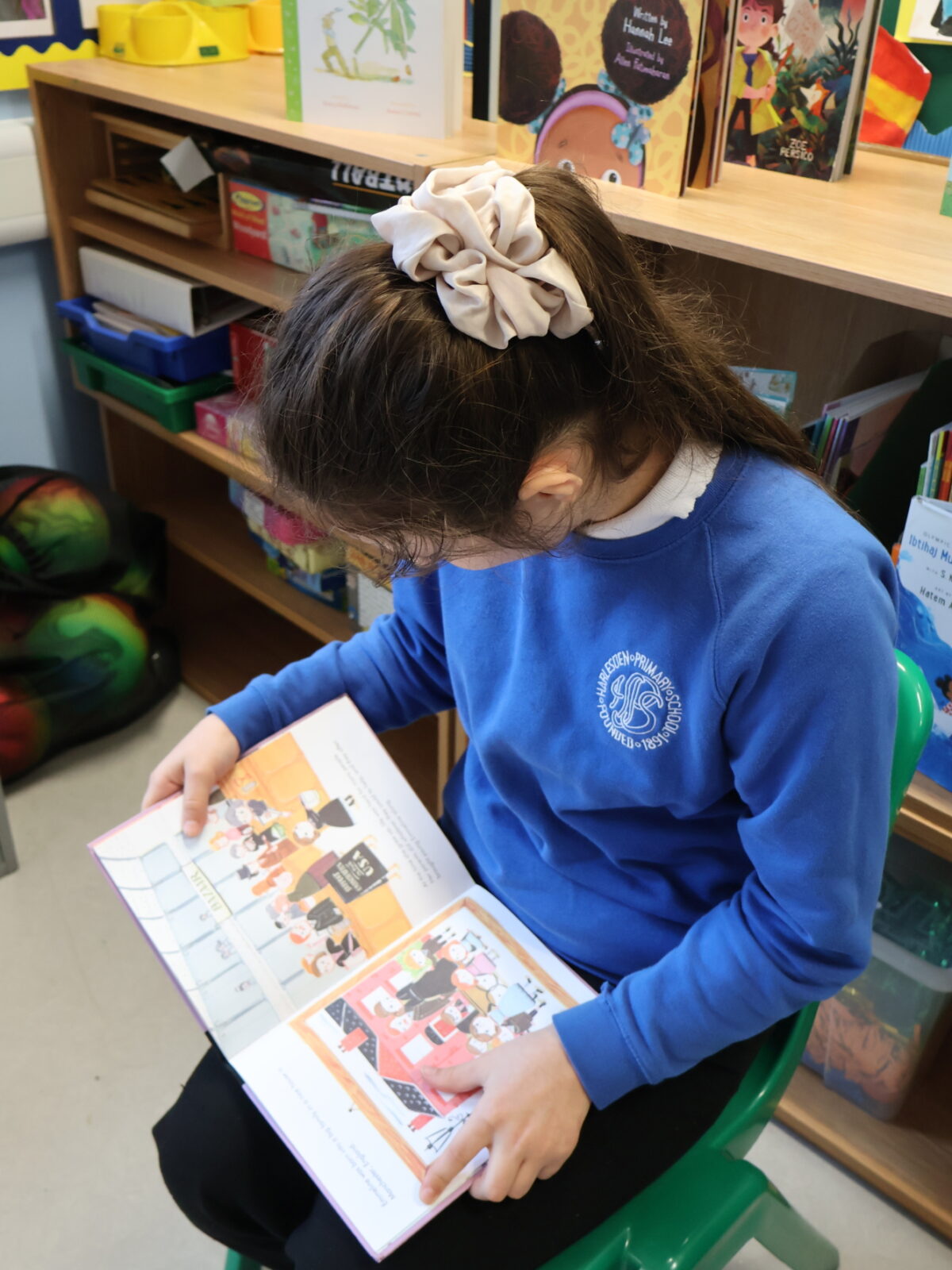 Girl in blue school uniform with a book open on a page.