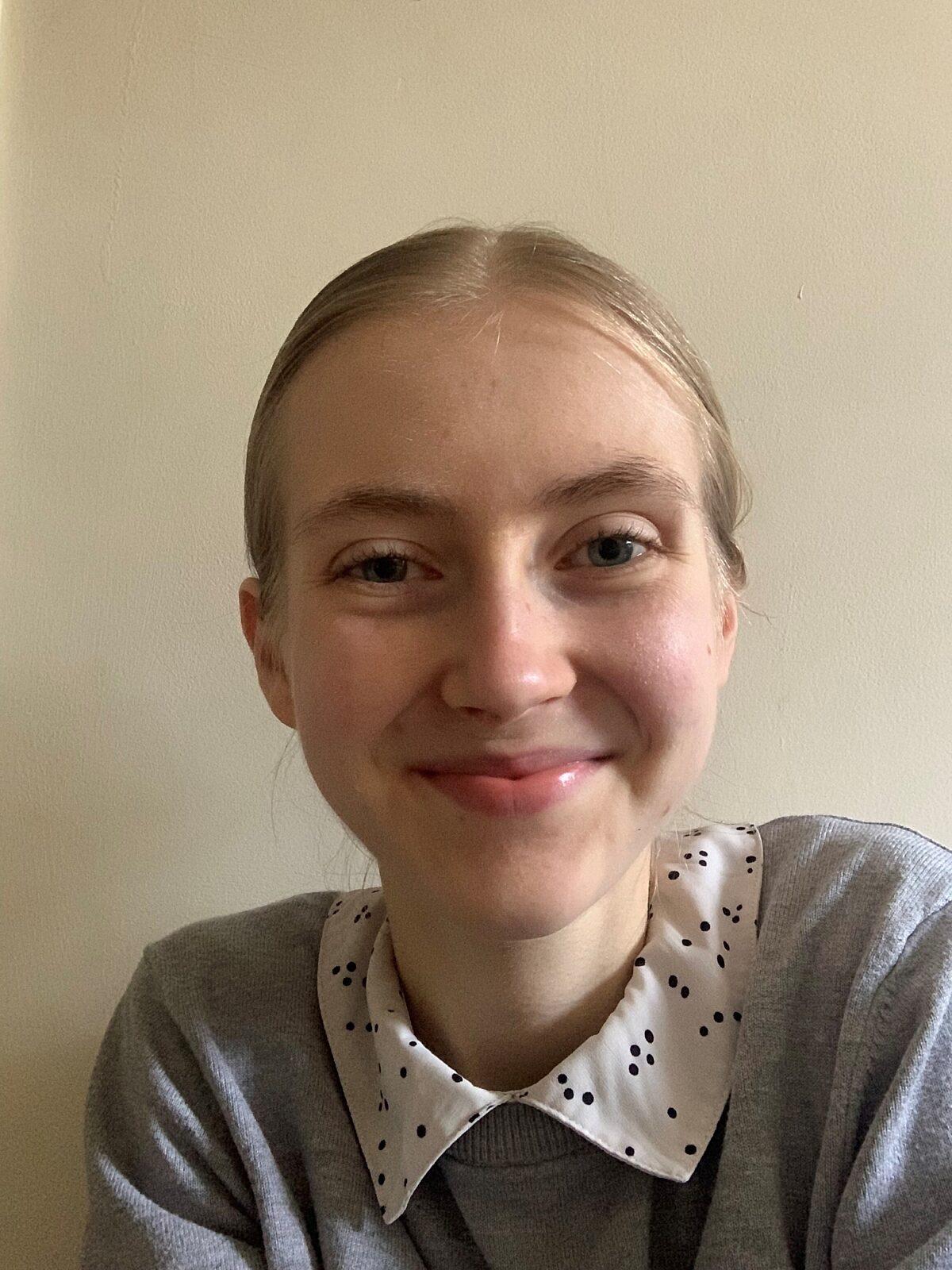 Selfie shot of young reading volunteer smiling at the camera. She's got blonde hair in a pony tail and is wearing a grey jumper.