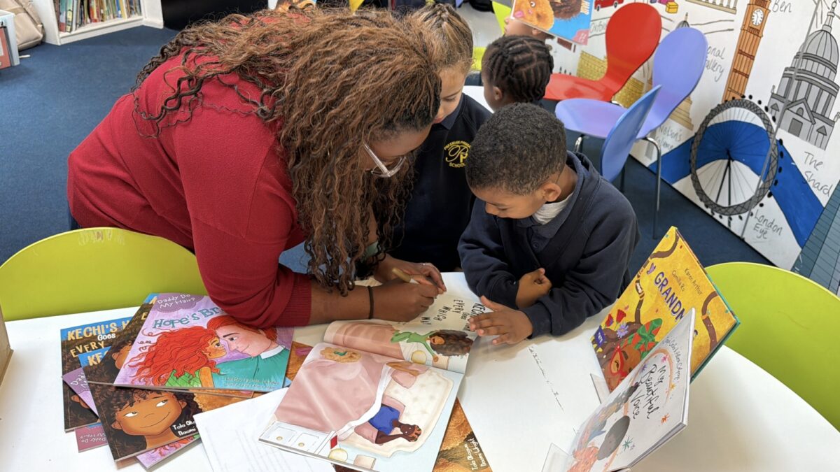 Tola Okogwu signing a book for a child during a school literacy event, supported by Bookmark.