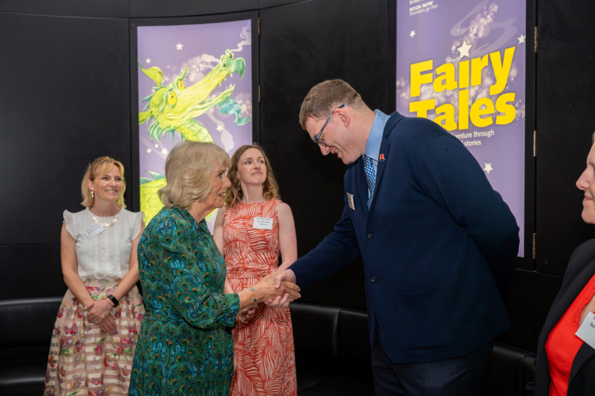 A man in a suit shakes hands with a woman in a green dress