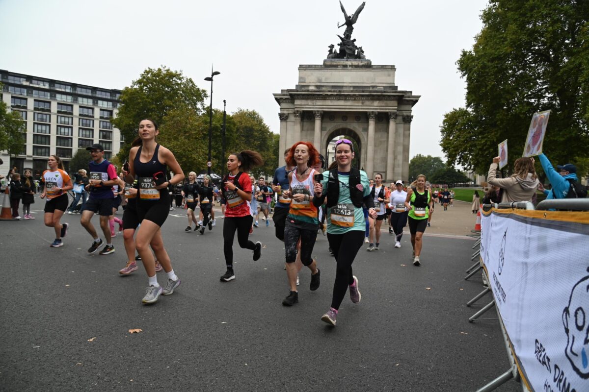 Bookmark runner running through London, she's smiling at the camera with The Wellington Arch behind.