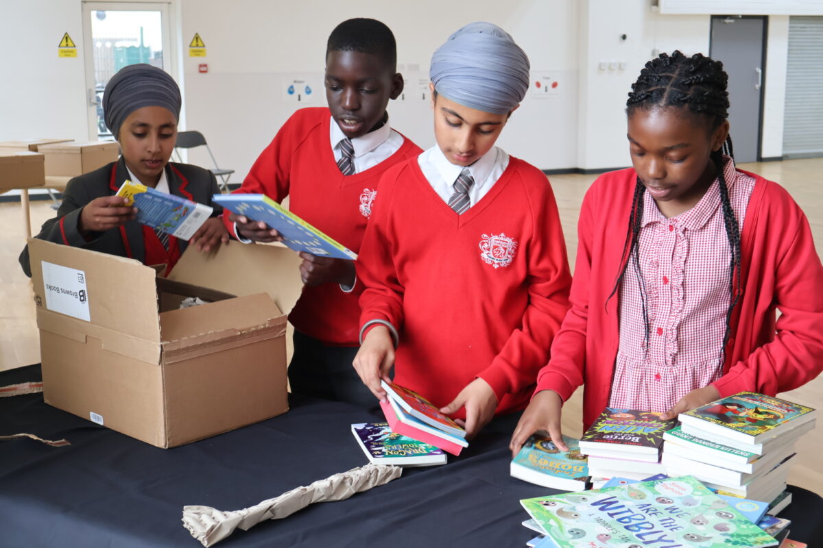 4 children in red school uniform open a box of books