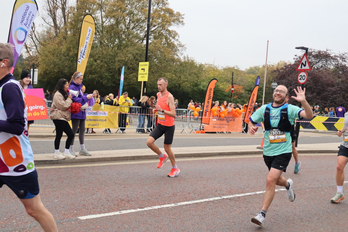 Runner in Bookmark t-shirt waving to the camera as he runs past.