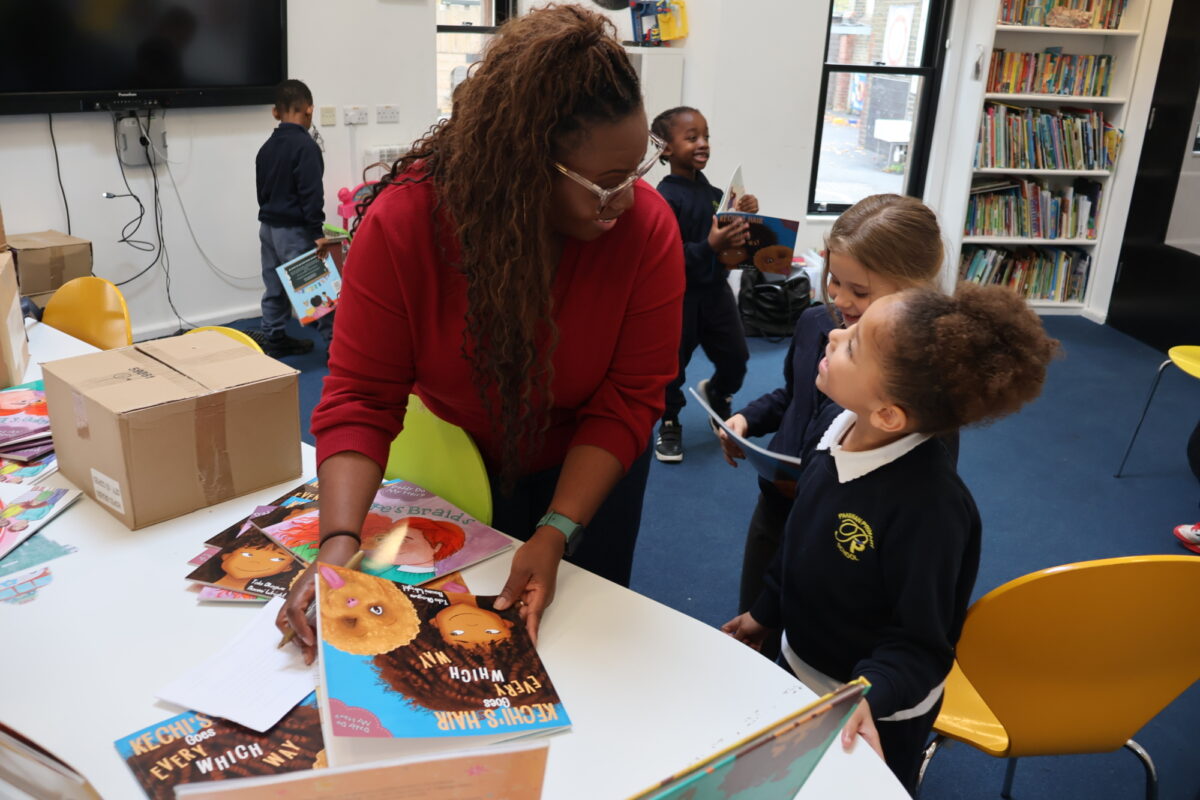 A girl smiles up at a woman, holding books