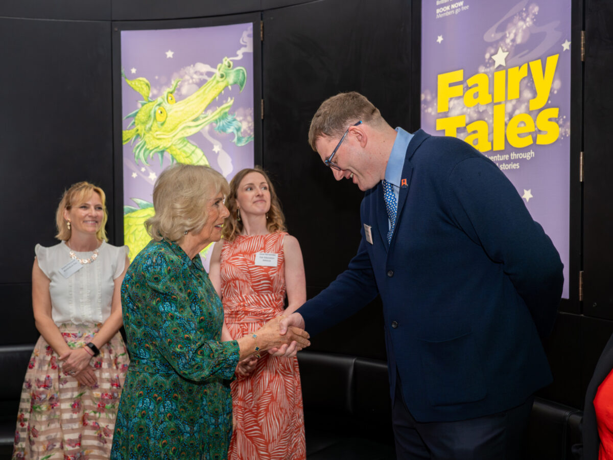 A man in a suit shakes hands with a woman in a green dress