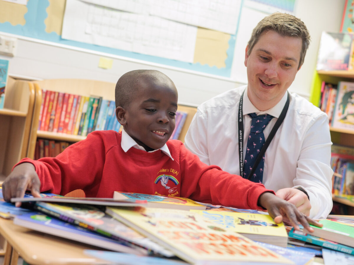 Child and teacher reading a book from Bookmark's roots to reading programme.