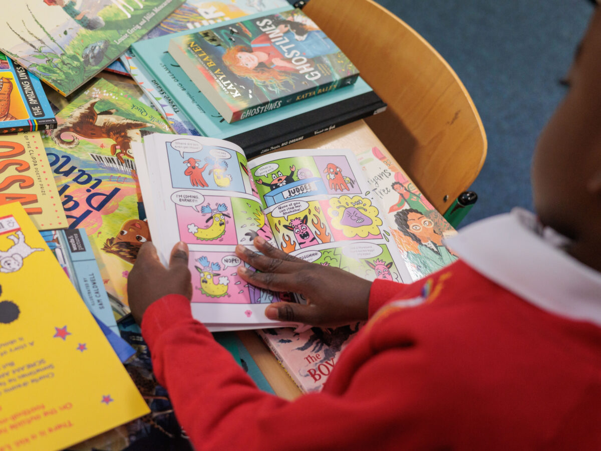 child reading a book from Bookmark's roots to reading programme. He's pointing to a section of the book.