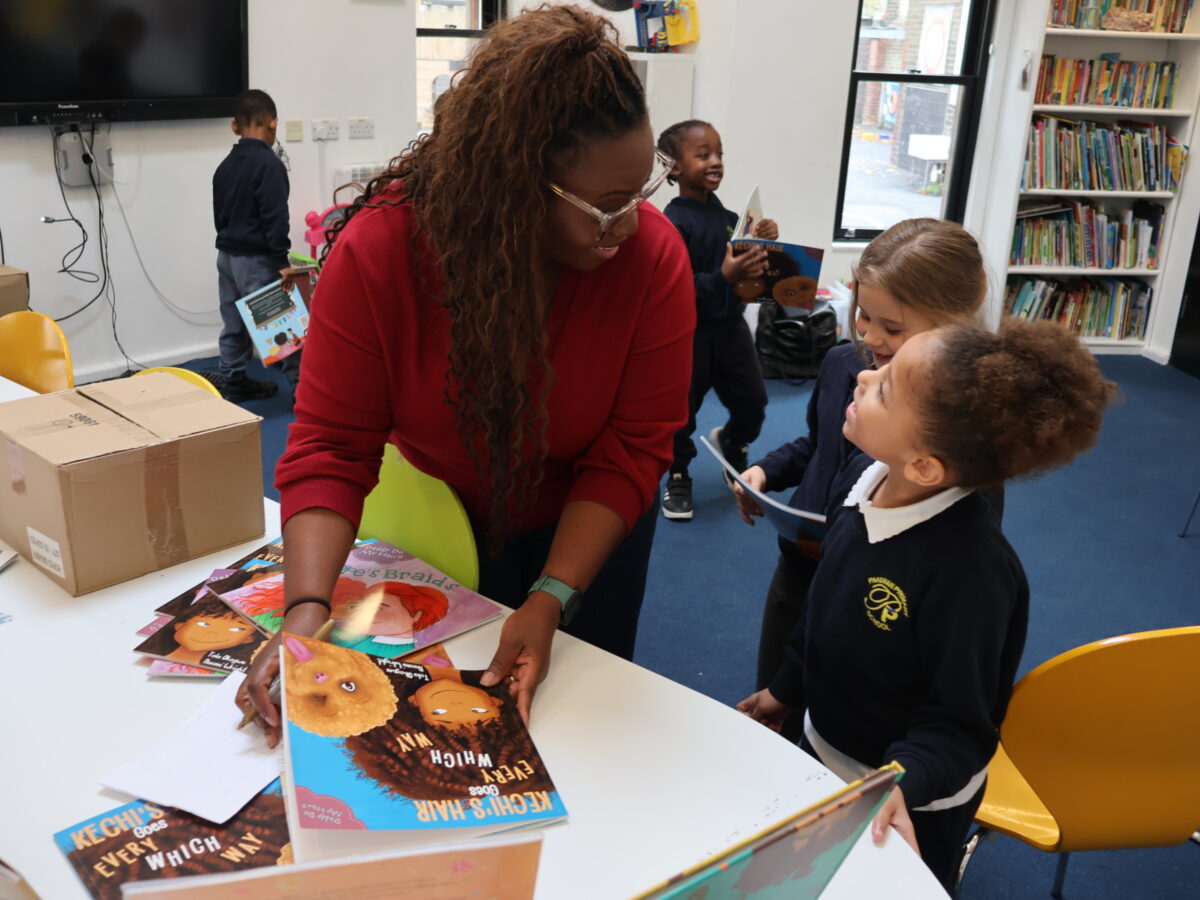 A girl smiles up at a woman, holding books