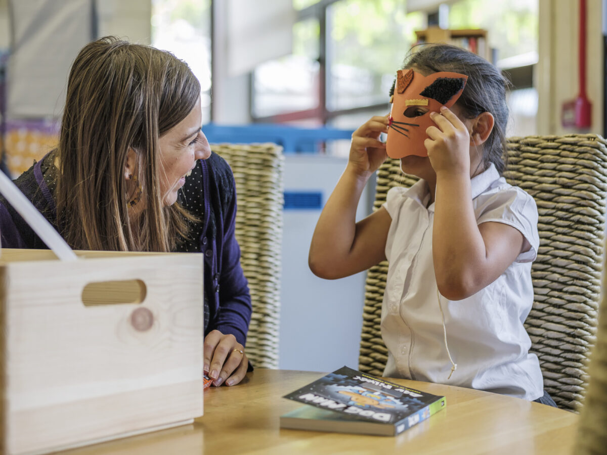 A bookmark volunteer and a child explore a Bookmark box of literacy games and books together at a in-person reading session.