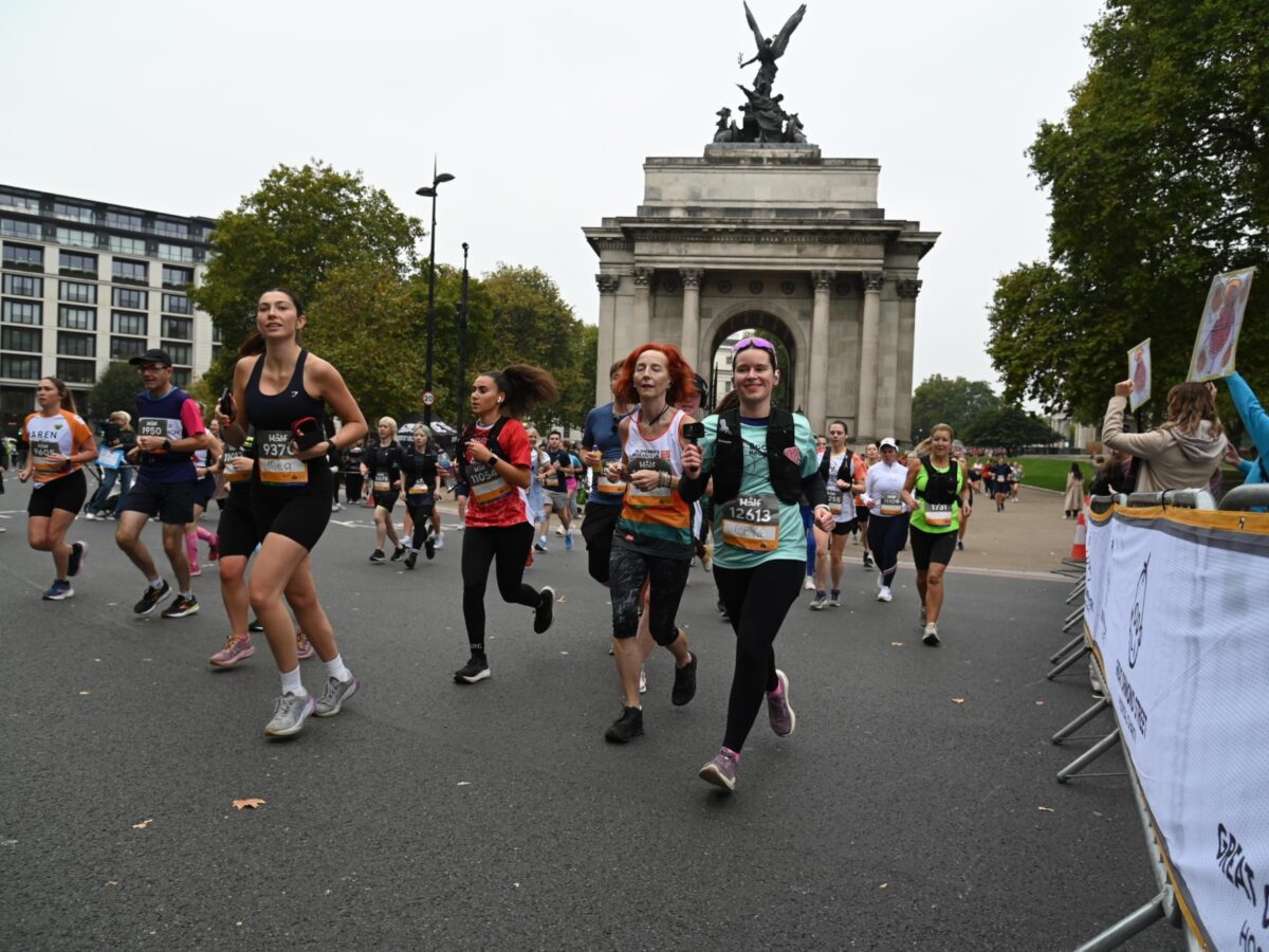 Bookmark runner running through London, she's smiling at the camera with The Wellington Arch behind.