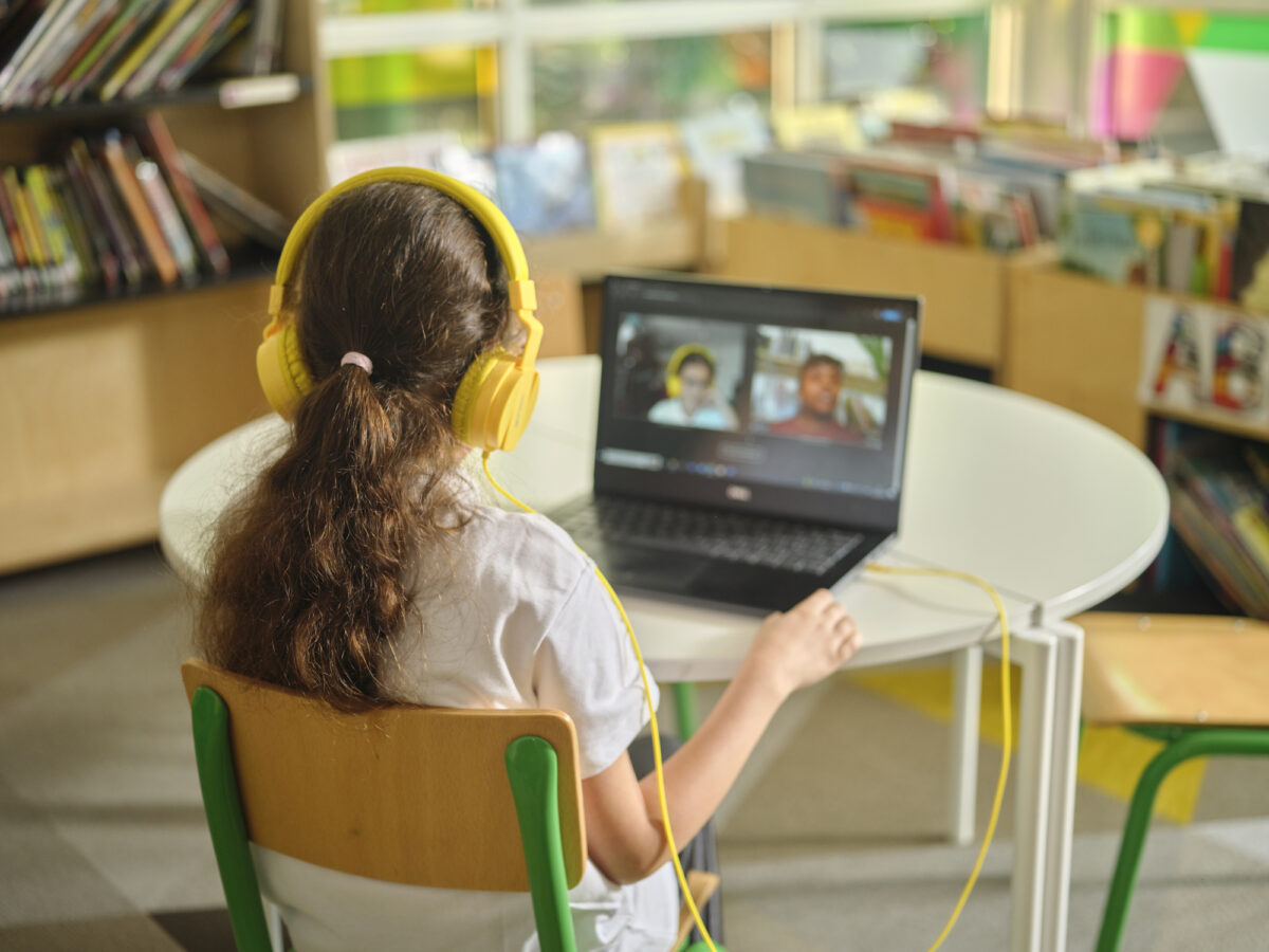 Girl with brown ponytail in an online reading session with her volunteer.