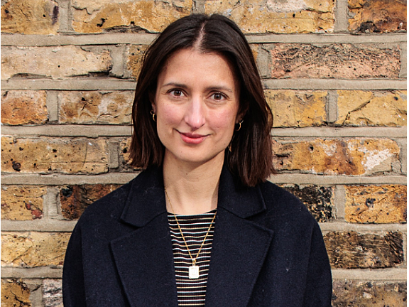 Woman with brown short hair, and a black blazer smiling at the camera.