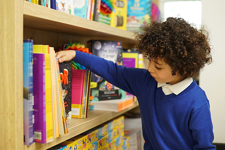 A child choosing a book from a school bookshelf