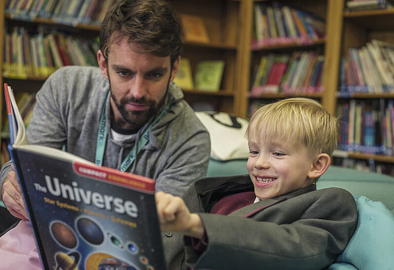A Bookmark volunteer and child reading together in a school library