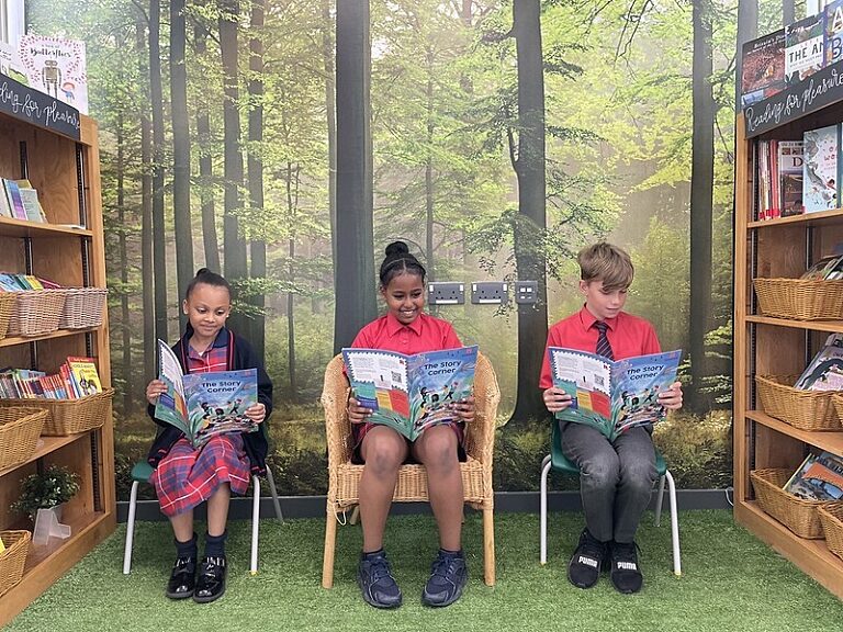 Three children sat in separate chairs reading The Story Corner magazine