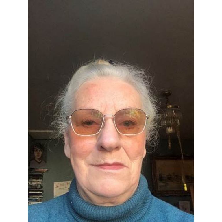 Bookmark volunteer headshot, she's wearing a blue polo neck jumper and has tinted glasses.