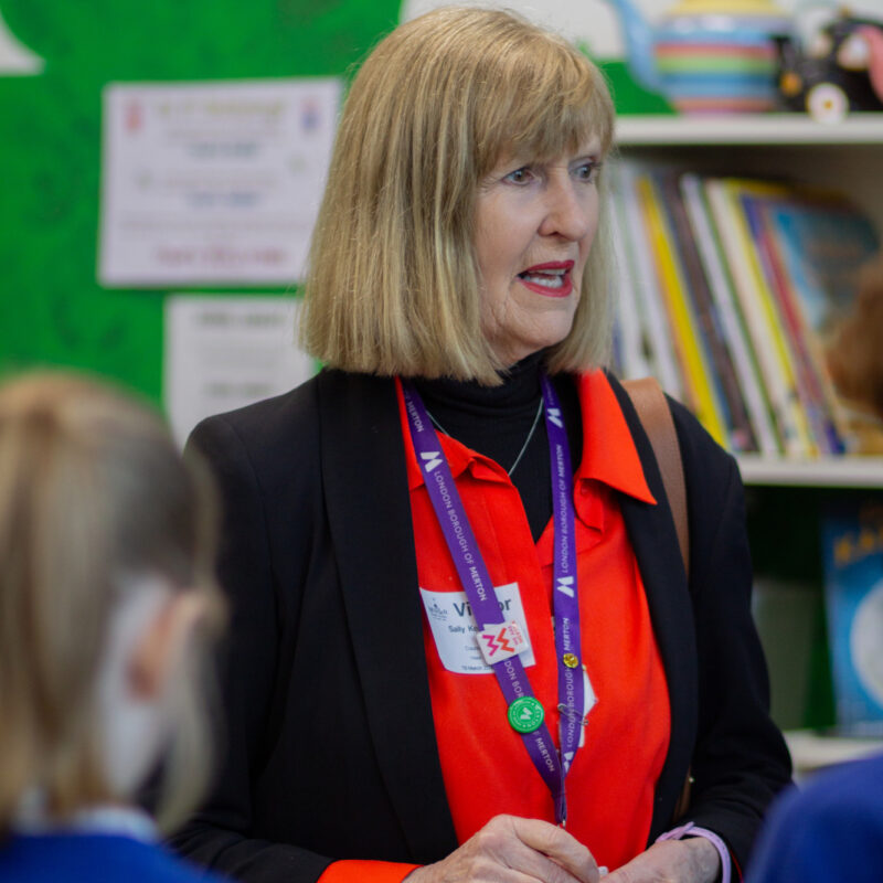 Local Cabinet Member, Sally Kenny, standing with children as part of Bookmarks roots to reading programme.