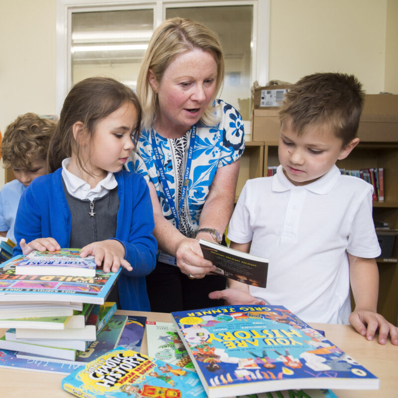 Volunteer reading with primary school children, helping to build literacy skills and encourage reading for pleasure.