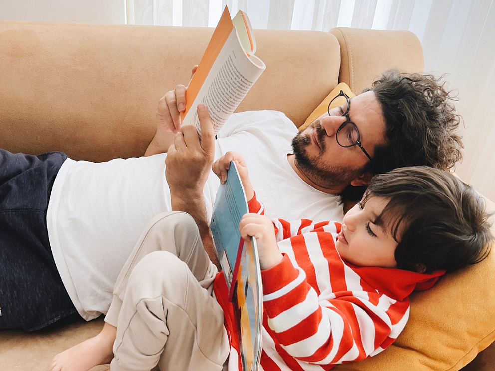 Adult and child reading books together at home to help prevent summer learning loss.