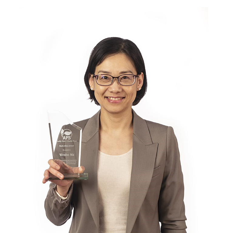 Photograph of Wenbo Ma against a white background. Wenbo is holding the Ruth Allen Award trophy in her right hand.